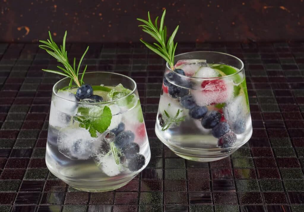 Gin tonic decorated with a rosemary sprig and fresh berries